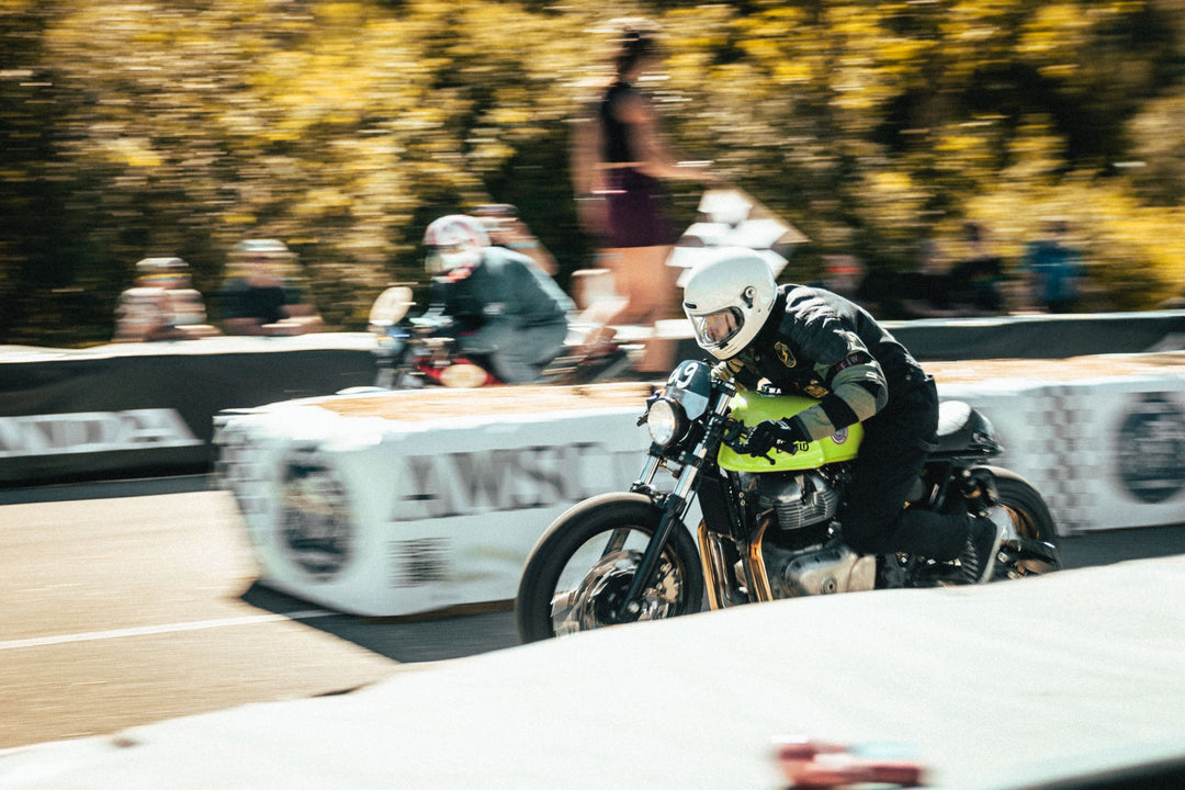 Motorradfahrer auf einer grünen Rennmaschine mit Startnummer 49 beim Sprint, mit einem zweiten Fahrer im Hintergrund.