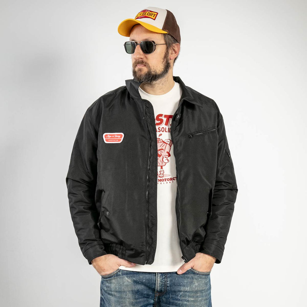 Schwarze Age of Glory Paddock Nylonjacke, offen über einem weissen T-Shirt getragen.